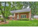 Beautifully landscaped yard showcasing a classic brick facade, windows, and front entrance with steps at 7050 Knightswood Dr, Charlotte, NC 28226