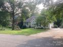 This exterior shows a well-maintained home with a lush, green lawn and mature trees with street access and driveway at 1369 Timberlane Ter, Mooresville, NC 28115