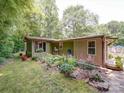 View of the home's back exterior with its screened-in porch, garden, and landscaping at 157 Old Hearth Rd, Clover, SC 29710