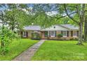 Attractive brick home with classic black shutters and a well-maintained front lawn with mature foliage at 1961 Runnymede Ln, Charlotte, NC 28211