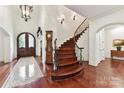 Grand foyer with hardwood floors, a curved staircase, and a decorative rug and chandelier at 2240 La Maison Dr, Charlotte, NC 28226