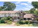 Charming Tudor-style home with brick and stucco accents, surrounded by mature landscaping and greenery at 24008 Carriker Rd, Albemarle, NC 28001