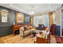 Elegant living room featuring dark wall paneling, a chandelier, and hardwood floors at 5357 Pembrey Dr, Denver, NC 28037
