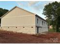 A look at the side of a single story home with light gray siding and a brick foundation on a large lot at 63 Cornerstone Dr, Taylorsville, NC 28681