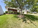 Well-maintained front yard featuring a mature tree and lush green lawn in a residential neighborhood at 1228 Tranquil Falls Ln, Matthews, NC 28104