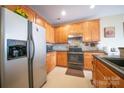 Functional kitchen with stainless steel appliances, wood cabinets, and gray countertops at 16525 Kettlewell Ln, Charlotte, NC 28277