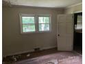 Shows a bedroom with damage to the hardwood floor, light walls, and two windows at 1769 S Nc 16 Hwy, Denver, NC 28037
