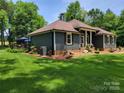 Side view of well-maintained home with landscaped yard, featuring a deck and manicured lawn at 2777 Old South Nw Ct, Concord, NC 28027
