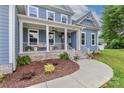 Inviting front porch with brick steps, white railing, seating, and a wood front door at 332 Canvasback Rd, Mooresville, NC 28117