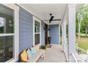 Cozy front porch with a ceiling fan, wood door, seating with decorative pillows and plants at 332 Canvasback Rd, Mooresville, NC 28117