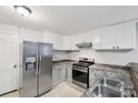 Galley kitchen featuring stainless steel appliances, white cabinets, and stone-look countertops at 407 Cherry St, Belmont, NC 28012