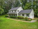 Two-story home with a well-manicured lawn, attached garage and black shutters surrounded by mature trees at 4848 Spicewood Dr, Charlotte, NC 28227