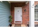 Close-up of a white front door with brick trim, a welcome mat, and decorative plants at 8906 Pickering Grove Ln, Charlotte, NC 28216