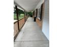 Long covered front porch with new wood railing, brick accents and access to a hanging chair at 10672 Barberville Rd, Fort Mill, SC 29707