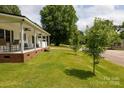 A charming single-story home showcasing a well-maintained lawn, mature trees, and a welcoming covered front porch at 1197 Fincher Rd, Fort Lawn, SC 29714
