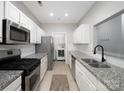 Galley kitchen with stainless appliances, granite countertops, white cabinets and in-unit laundry at 5617 Fairview Rd # 9, Charlotte, NC 28209