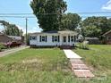Quaint single-story home featuring a green lawn, sidewalk, and mature trees at 6225 Macon St, Charlotte, NC 28208