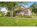 Inviting two-story home with lush green lawn, mature trees, and a charming front porch at 6533 Derby Nw Ln, Concord, NC 28027