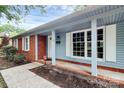 Close up of charming porch with brick facade and blue wood siding featuring a modern white front door at 7118 April Ridge Ln, Charlotte, NC 28215