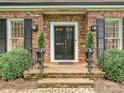 Close up of the front door, featuring brick steps, black shutters, and decorative landscaping at 828 Colville Rd, Charlotte, NC 28207