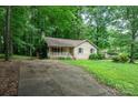 A rustic one-story home with a brick exterior, accessed by a driveway, nestled among trees and green landscape at 1802 Deer St, Charlotte, NC 28214