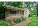 A charming brick home features a cozy front porch, complemented by green landscaping and mature shade trees at 1802 Deer St, Charlotte, NC 28214