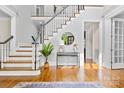 Elegant foyer features hardwood floors, a staircase with white spindles, and a decorative round mirror at 1806 Asbury Hall Ct, Charlotte, NC 28209