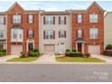 Attractive townhome with red brick accents, neutral siding, manicured landscaping, and a one-car garage at 2169 Belle Vernon Ave, Charlotte, NC 28210