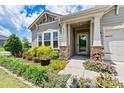 Beautiful home entrance with meticulously arranged landscaping, colorful flowers, and stone detailing on the porch at 4197 Canopy Creek Dr, Denver, NC 28037