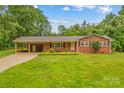 Charming brick home featuring a well-manicured lawn, mature trees, and a convenient covered carport at 44092 Woodhurst Rd, New London, NC 28127