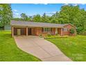 Inviting brick home with a long driveway, a carport, and a well-kept lawn with mature landscaping at 44092 Woodhurst Rd, New London, NC 28127