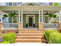 Inviting front porch with brick accents, white columns, and lush greenery, perfect for relaxing at 5518 Morris Hunt Dr, Fort Mill, SC 29708