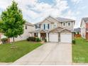 Inviting two-story home featuring a stone facade, spacious driveway, and lush green lawn at 6532 Prosperity Commons Dr, Charlotte, NC 28269