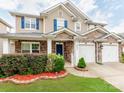 Attractive two-story home with stone accents, a blue front door, and landscaped garden beds at 6532 Prosperity Commons Dr, Charlotte, NC 28269