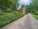 View of a red brick home featuring a long driveway and detached garage at 220 Lakeview Dr, Belmont, NC 28012