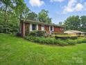 Red brick home featuring a tidy lawn and vibrant landscaping at 220 Lakeview Dr, Belmont, NC 28012