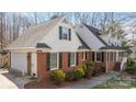 Side view of brick home with attached garage, dormer windows, and mature landscaping at 3500 Sunningdale Ln # 221, Statesville, NC 28625