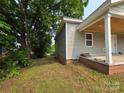 Side view of a home featuring gray siding, a brick foundation, and a covered porch with wooden ceiling at 38 Holly St, Great Falls, SC 29055