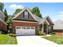 Charming brick home with a two-car garage, stone accents, manicured lawn and plentiful bushes and small shrubs at 4004 Saint Andrews Ct, Cramerton, NC 28032