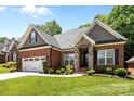 Charming brick home with a two-car garage, stone accents, manicured lawn and plentiful bushes and small shrubs at 4004 Saint Andrews Ct, Cramerton, NC 28032