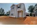 New construction two-story home features gray siding, black shutters, and a covered front porch, blending modern design with classic charm at 4040 Grommet Ct, Matthews, NC 28105