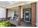 Inviting front porch with rocking chairs, decorative wood columns, and a stylish blue front door at 482 Lucky Nw Dr, Concord, NC 28027