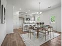 A dining room with modern light fixtures, neutral-toned chairs, and a kitchen view at 5236 Hatcher Creek Rd # 52, Charlotte, NC 28215