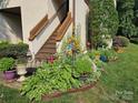 Charming front entrance with a colorful garden and wooden staircase leading to the upper level at 7329 Winery Ln, Charlotte, NC 28227