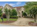 Charming home exterior with a circular driveway, lush landscaping, and mature trees at 7600 Dunsmuir Ct, Cornelius, NC 28031