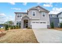Two-story home showcasing gray siding, stone accents, a two-car garage and a well-manicured lawn against a bright blue sky at 9934 Cask Way, Huntersville, NC 28078