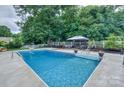 Refreshing backyard pool with lounge area and a white picket fence surrounded by lush greenery, perfect for relaxation at 10304 Squires Way # 18, Cornelius, NC 28031