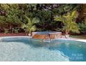 Beautiful in-ground pool with a stone waterfall feature and mature landscaping, creating a serene outdoor oasis at 1103 Mapesbury Ln, Waxhaw, NC 28173