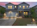 Charming two-story home with a two-car garage and stone veneer accents at dusk at 12536 Stoneybrook Pkwy, Huntersville, NC 28078