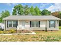 Charming single-story home features neutral siding, black shutters, well-maintained yard, and inviting front porch at 1316 Wiscassett St, Albemarle, NC 28001